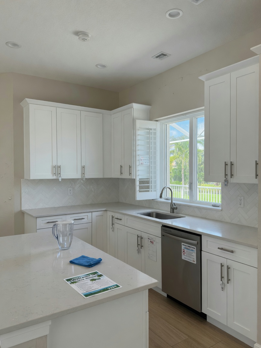 Ultra-realistic 8K photo of modern commercial kitchen cabinets with white shaker doors and stainless steel handles installed in a Southwest Florida rental property kitchen in Alico, bright natural lighting, clean countertops, 33967 area home interior